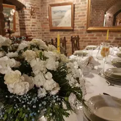 Elegancko nakryty stół z bukietem białych kwiatów i dzbankiem soku. Idealne miejsce, gdzie dobrze zjeść w Nałęczowie.