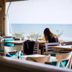 Kobieta siedzi przy stoliku w restauracji z widokiem na morze. Idealne miejsce, gdzie zjeść we Władysławowie.