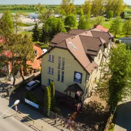 Port Regna - idealne miejsce, gdzie rezerwować noclegi. Obok pomarańczowa kamienica, zielone drzewa i słoneczny dzień.