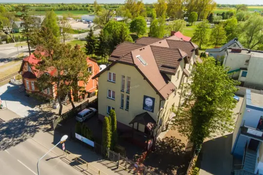 Port Regna - idealne miejsce, gdzie rezerwować noclegi. Obok pomarańczowa kamienica, zielone drzewa i słoneczny dzień.