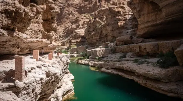 Wadi Shab w Omanie, idealne miejsce na wycieczki do Omanu. Zielona woda w kanionie, skalne ściany.