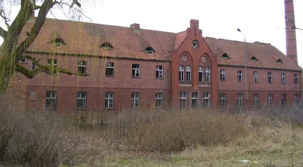 Opuszczony budynek z cegły, z charakterystycznymi okienkami na dachu, otoczony dziką roślinnością. Czy to najbardziej nawiedzone miejsce w Polsce?