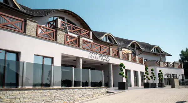 Elegancki hotel Molo Resort z drewnianymi balustradami i kamienną podmurówką. Sprawdź molo resort ceny i zarezerwuj pobyt.