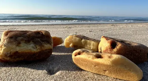 Kilka kawałków bursztynu leży na piaszczystej plaży. Warto wiedzieć, jak rozpoznać bursztyn na plaży, by cieszyć się skarbami Bałtyku.