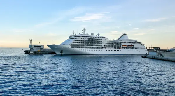 Biały statek wycieczkowy cumuje przy nabrzeżu. W tle błękitne niebo z chmurami. Zastanawiasz się, ile jest z Polski do Szwecji w linii prostej?