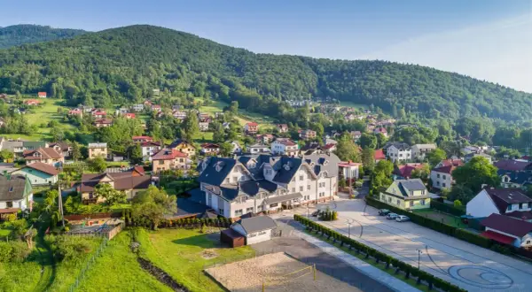 Widok na Hotel Skalite Spa & Wellness w Szczyrku, otoczony zielonymi wzgórzami i malowniczą zabudową.