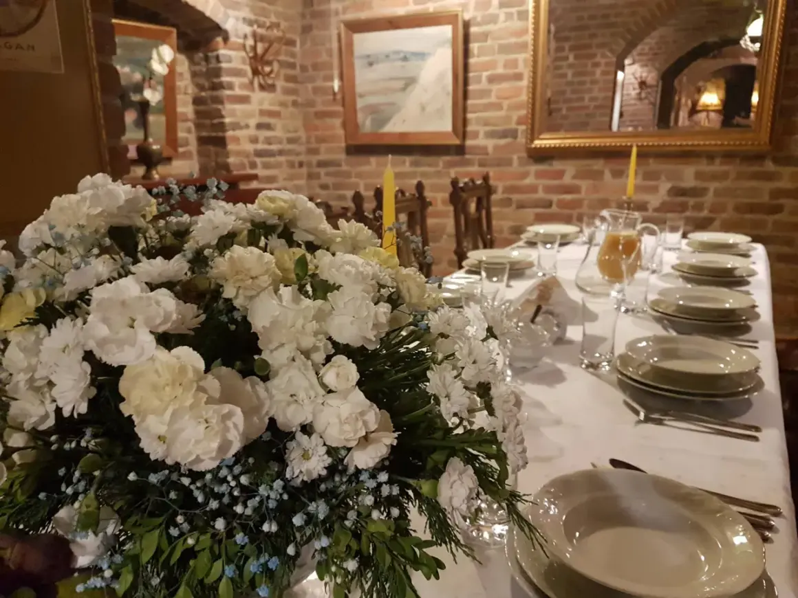 Elegancko nakryty stół z bukietem białych kwiatów i dzbankiem soku. Idealne miejsce, gdzie dobrze zjeść w Nałęczowie.
