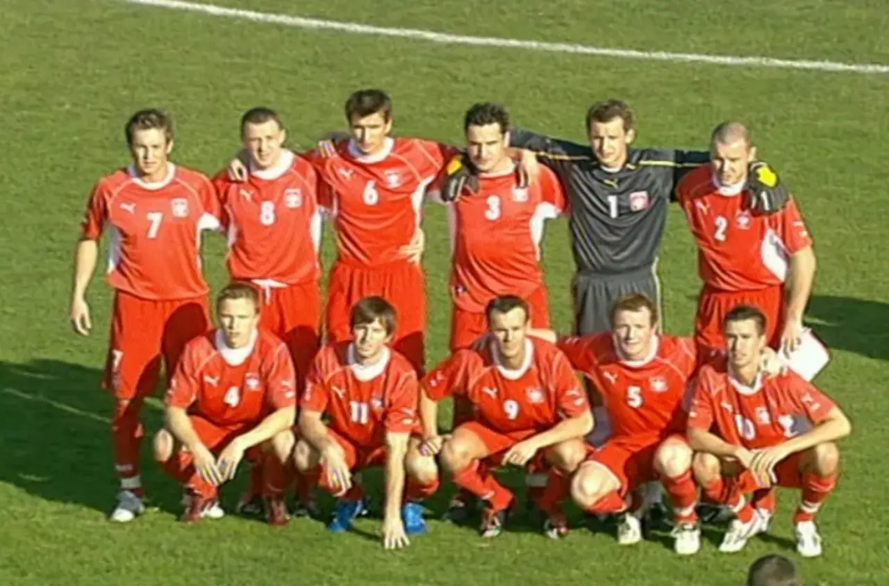 Drużyna piłkarska w czerwonych strojach, gotowa do gry. To polska owcze wyspy, które zdobywają serca kibiców.