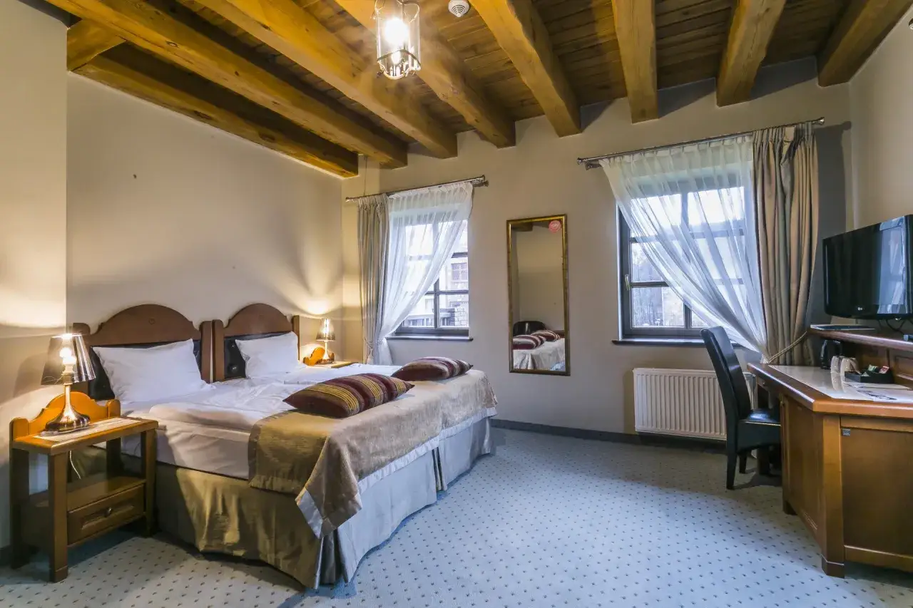 Przytulny pokój w hotelu Aubrecht Country Spa Resort Koprzywnica z drewnianym sufitem, wygodnym łóżkiem i biurkiem.