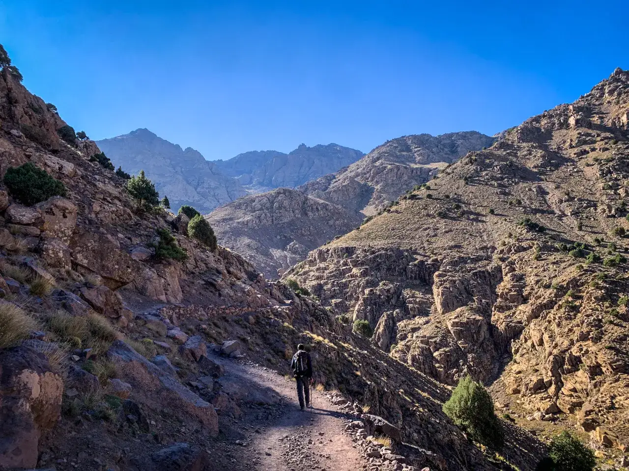 Samotny turysta na szlaku podczas jebel toubkal trekking. Górzysty krajobraz Maroka pod błękitnym niebem.