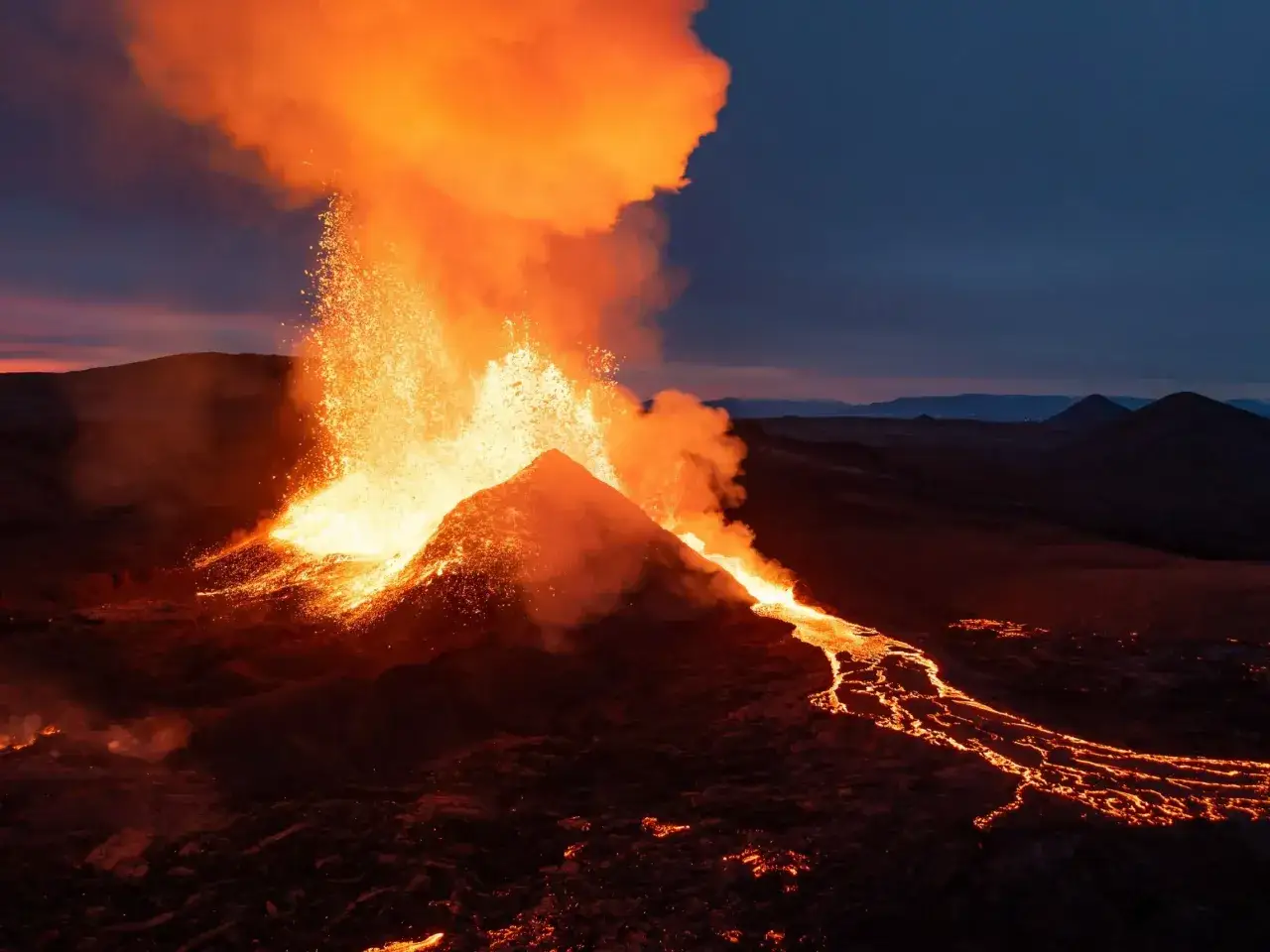 Potężna erupcja czynnych wulkanów na Islandii. Gorąca lawa spływa po zboczu, a popiół unosi się w ciemniejącym niebie.