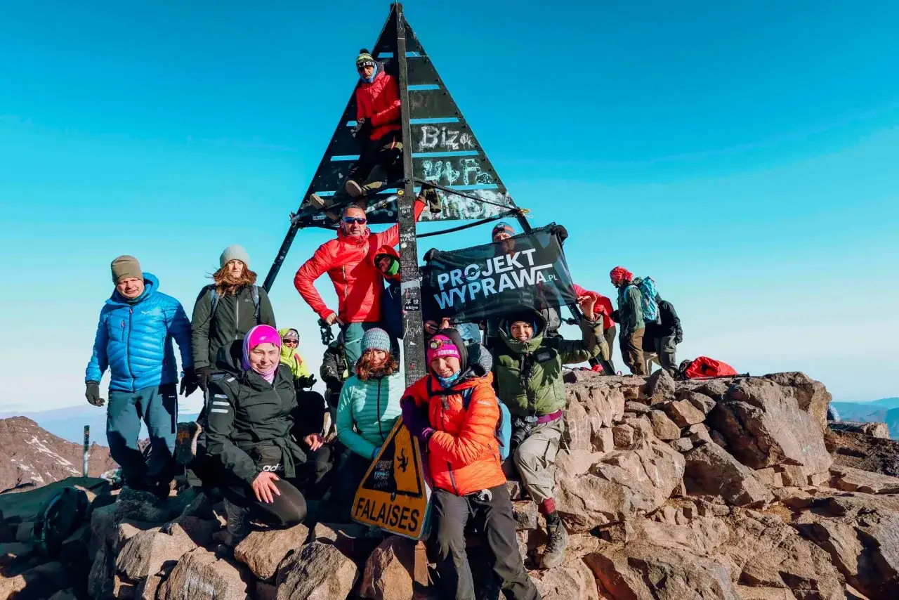 Grupa zdobywców na szczycie Jebel Toubkal podczas trekkingu, z banerem