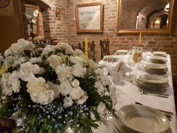 Elegancko nakryty stół z bukietem białych kwiatów i dzbankiem soku. Idealne miejsce, gdzie dobrze zjeść w Nałęczowie.